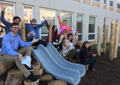 Teachers seated on stumps cheer for new playspace